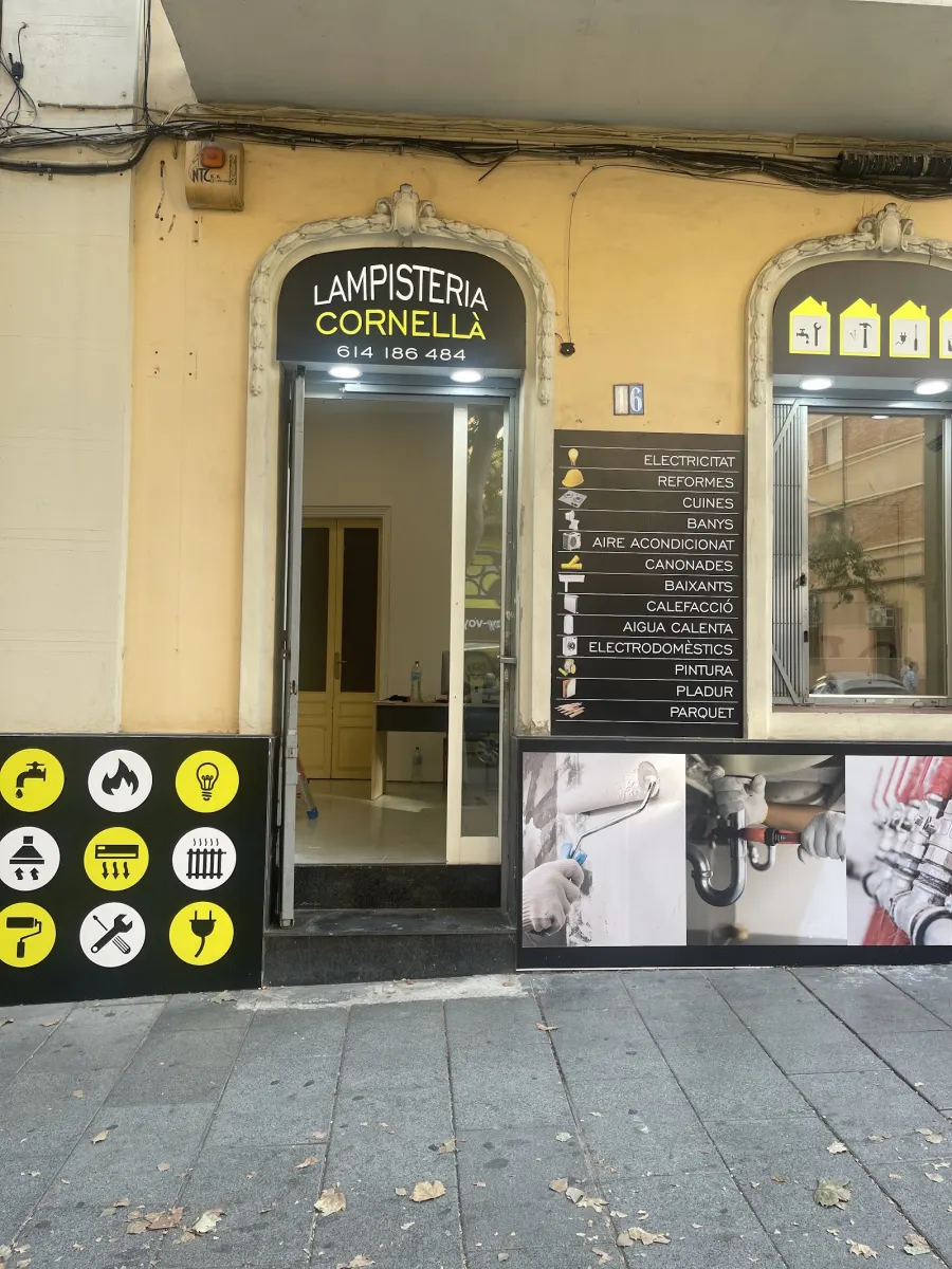 Fachada de la tienda Lampisteria Cornellà, con el rótulo y la lista de servicios junto a la puerta